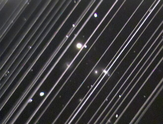 Snímek skupiny galaxií NGC 5353/4 byl pořízen dalekohledem na Lowellově observatoři v Arizoně 25. května 2019. Úhlopříčné čáry probíhající napříč snímkem jsou satelitní stopy odraženého světla z více než 25 družic Starlink, které prošly zorným polem dalekohledu. Kredit: Victoria Girgis/Lowell Observatory
